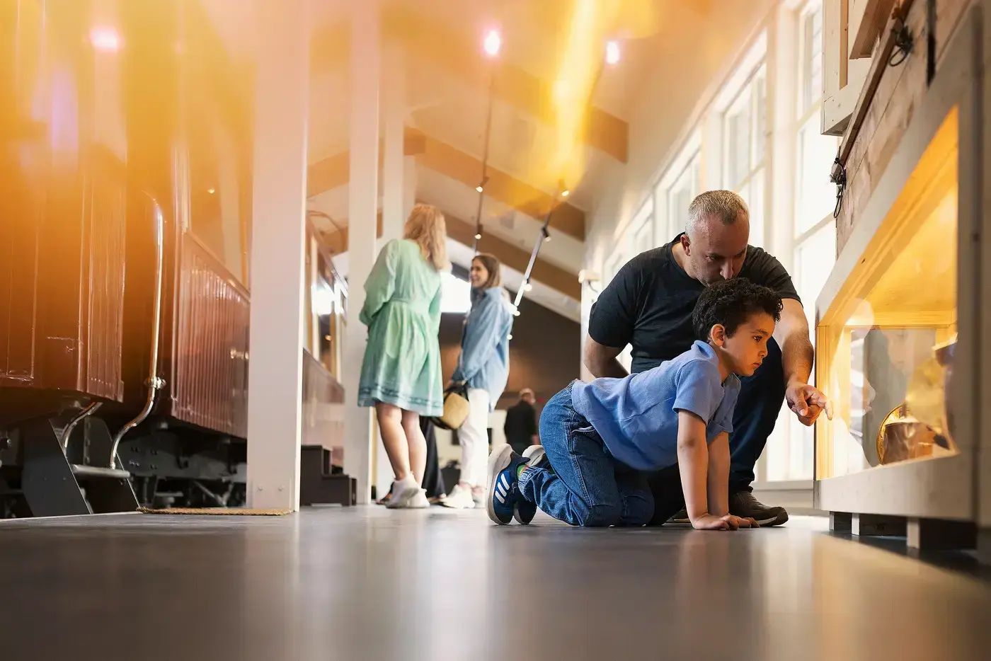 I forgrunnen en voksen og ett barn ser i monter i utstillingen Ut i verden. I bakgrunnen ser to personer på Kongevogna.