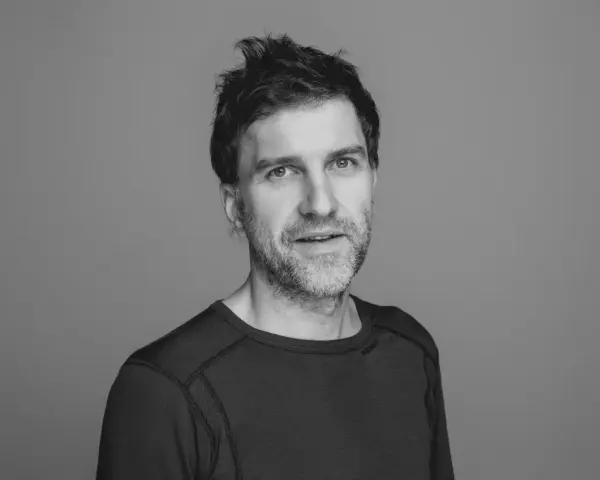 En mann med mørkt hår og mørk genser ser rett frem med et nøytralt blikk