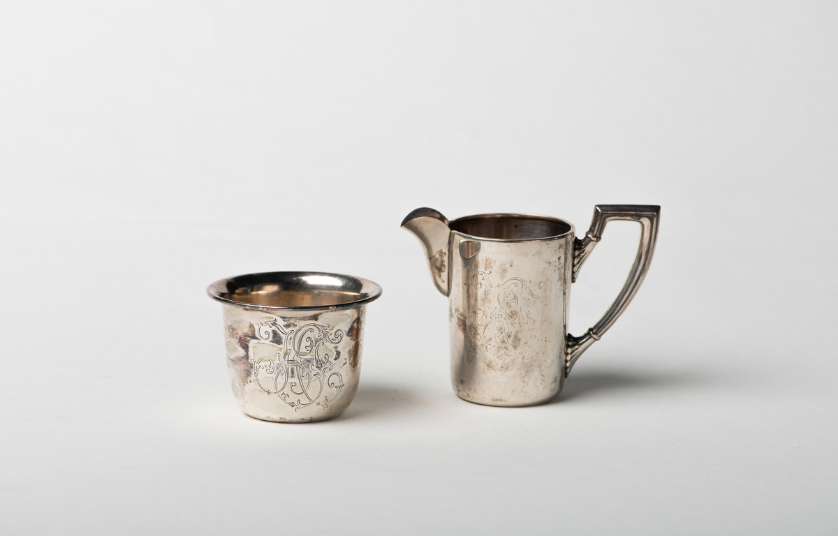 Sukkerkopp i begerform med inngravert monogram. Fløtemugge med riflet og knekket hank, korpus sylinderformet med bred tut. Monogram H F.