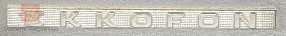 Rektangulær boks. Svart topp og bunn. Sidene er laget av tre. Fremsiden er av blankt metall, og det er fem knapper til forskjellige funksjoner. Det er også et panel på fremsiden som er mulig å åpne.
På baksiden er det en stikkontakt, samt inngang til båndopptaker, nettplugg og mikrofon. Det er også to ledninger som er festet på baksiden. Den ene er for strøm, mens den andre kan muligens være en nettverkskabel.
Det hører med en mikrofon til svareren. Denne er hvit og svart, og ledningen mellom svarer og mikrofon er svart.
Det hører også med en kassett som er hvit og merket med håndskrift: "defekt".