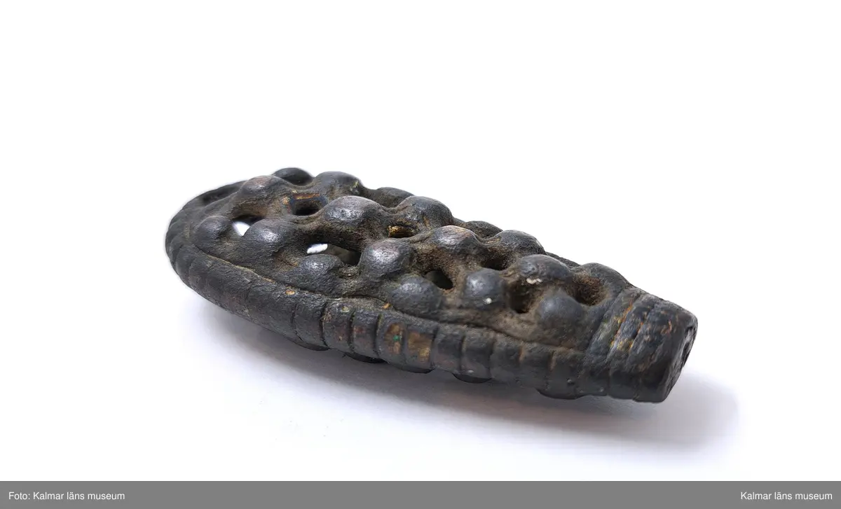 KLM 3102. Nyckel, nyckelskaft. Gjutet av brons. Handtaget är kraftigt spolformigt med genombruten ornamentik med knoppar. På sidorna tvärräfflad. Själva axet saknas.