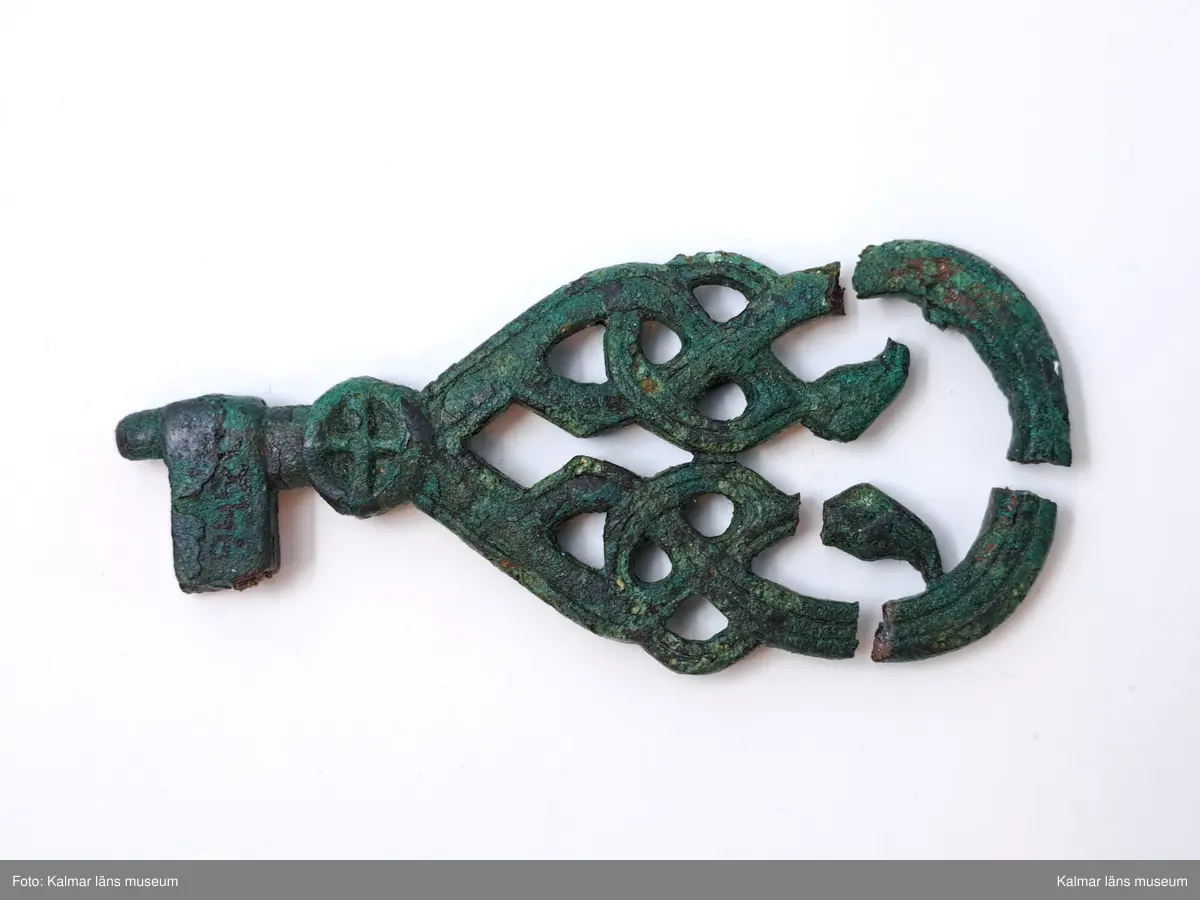 KLM 9420. Nyckel. Gjuten av brons. Skaftet är platt och har genombruten ornamentik med slingor. Skaftet övergår i en cirkelformad del med kors. Rektangulär form på axet.