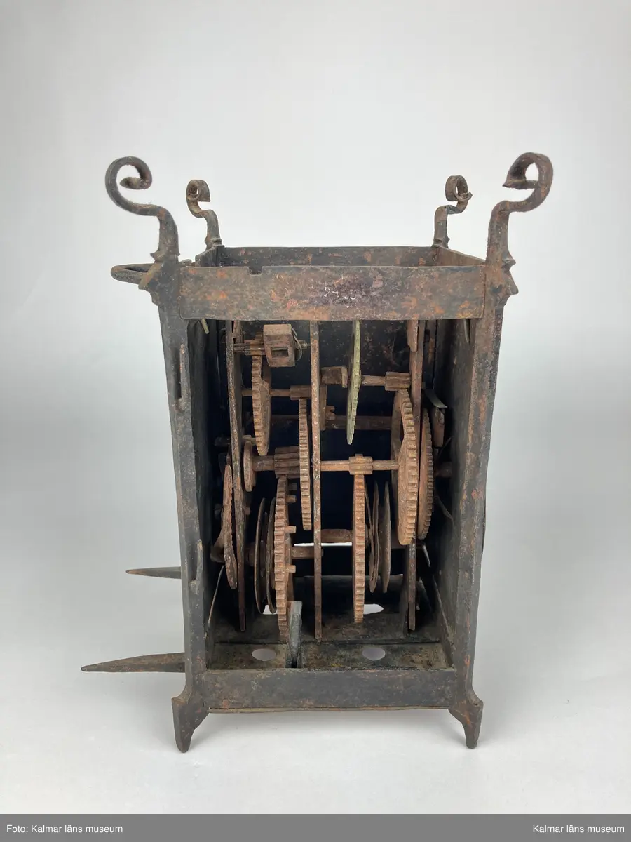 KLM 46893. Bordsur. Rektangulär stomme av järn med öppningsbara sidor, varav ena sidans dörr saknas. Upptill smidda detaljer. På ena sidan urtavla av mässing med stjärna i mitten, en visare av järn. Bakom urtavlan ett blekt pappersark i blågrönt. Urverk av järn och mässing. Uret har fyra fötter. På baksidan ögla av järn. Pendel, lodlinor, lod och trissor saknas.