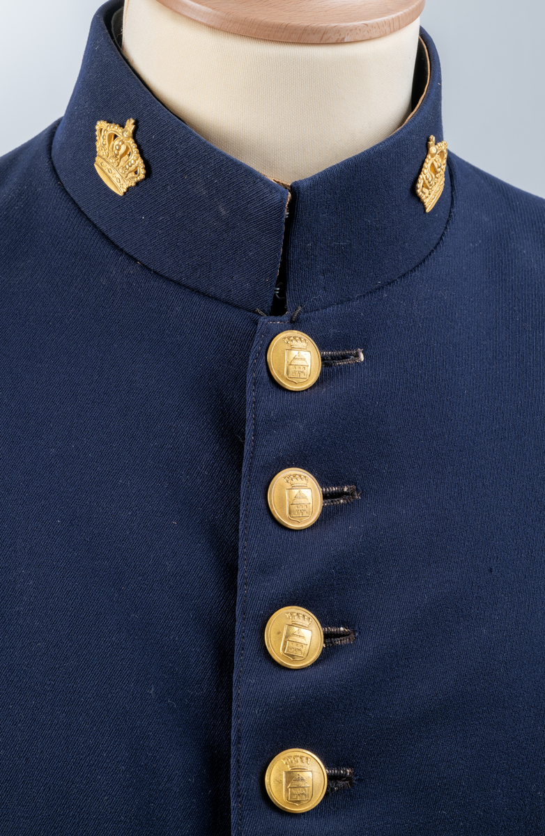 Uniformsjacka. Mörkblå. Enkel knäppning framtill med åtta knappar. På nedre delen av ärmarna tre mindre knappar. Sprund baktill med sex knappar. Alla uniformsknappar förgyllda och präglade med Växjö stadsvapen (år 1926-39). Kragmärke på var sida av ståndkragen, en förgylld kunglig krona med kudde.