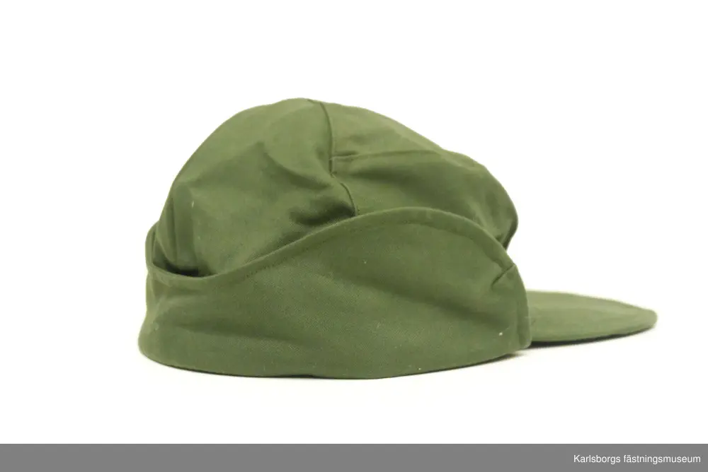 Fältmössa m/1959 är tillverkad av olivgrön varpsatin och är utförd med rundskuren kulle, stickad skärm med mellanlägg av smärting, nedfällbart slag av dubbelt tyg samt fodrat pannskydd. Märkt med tre kronor på insidan. Tillverkningsår: 1968. Storlek: 58.