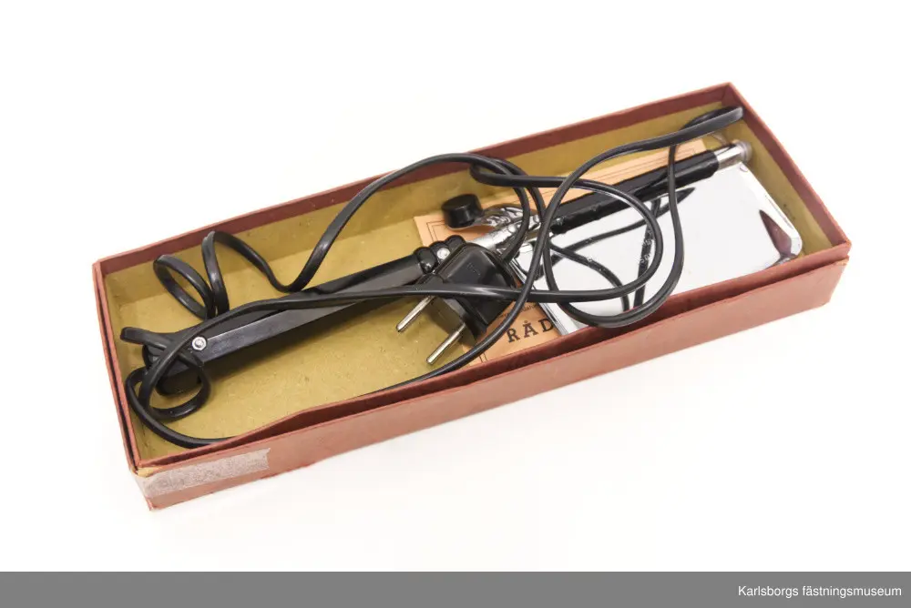 Empire Elektrisk Pressapparat från 1950-talet. Används för pressveck på plagg: byxor, kjolar, rockar, slipsar mm. Den kunde användas direkt på plagget och sägs ha skapat pressveck som kunde vara i flera veckor. Användningen gick till såhär: först fick pressapparaten värmas upp i ungefär tre minuter för att sedan föra den sakta efter vecket så att den glider fint. Plagget skulle inte sträckas ut under arbetet. Pressen kunde inte överhettas och heller inte skada plagget. En garantisedel medföljer men leveransdatum saknas. Föremålet förvaras i sammanhörande låda. Tillverkat i Storbritannien. 