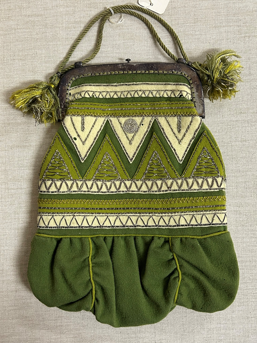 Av grönt tuskaftat ylle. Påsydda applikationer, broderi med silvertråd.