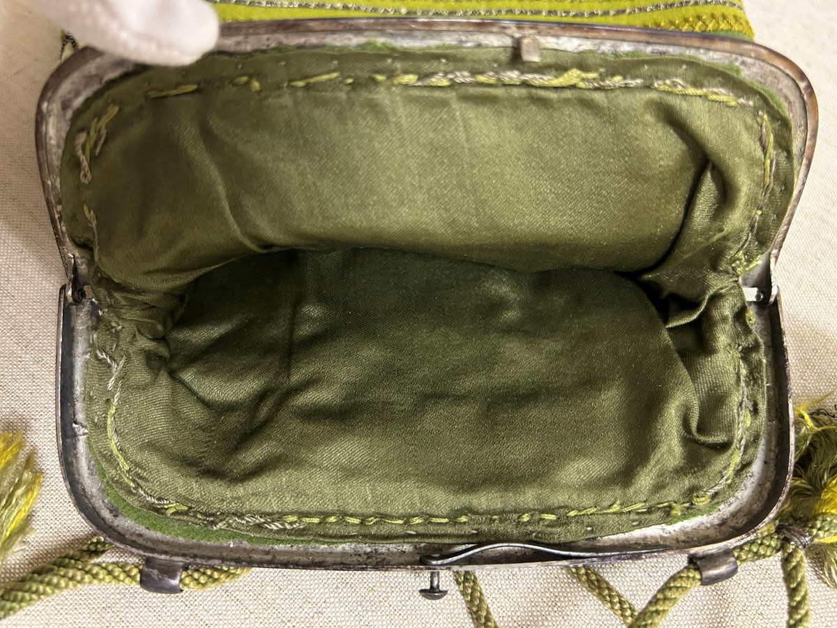 Av grönt tuskaftat ylle. Påsydda applikationer, broderi med silvertråd.