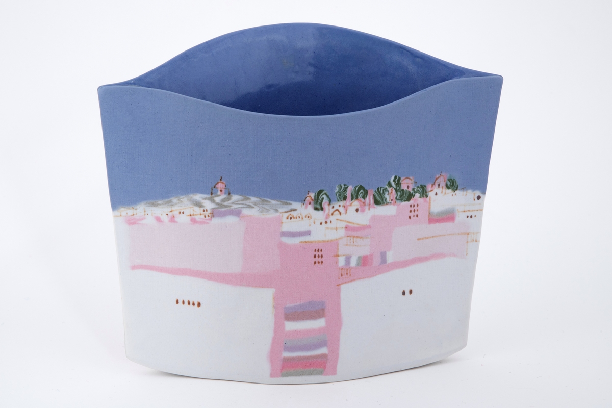 Flat vase sammensatt av to porselensflater. Den ene flaten er konveks oventil mens den andre er konkav. Begge flater prydes på inn- og utside av motiv i blått, hvit, rosa og grønt forestillende et bylandskap. Motivet er skapt med hjelp av innfarget porselen.
