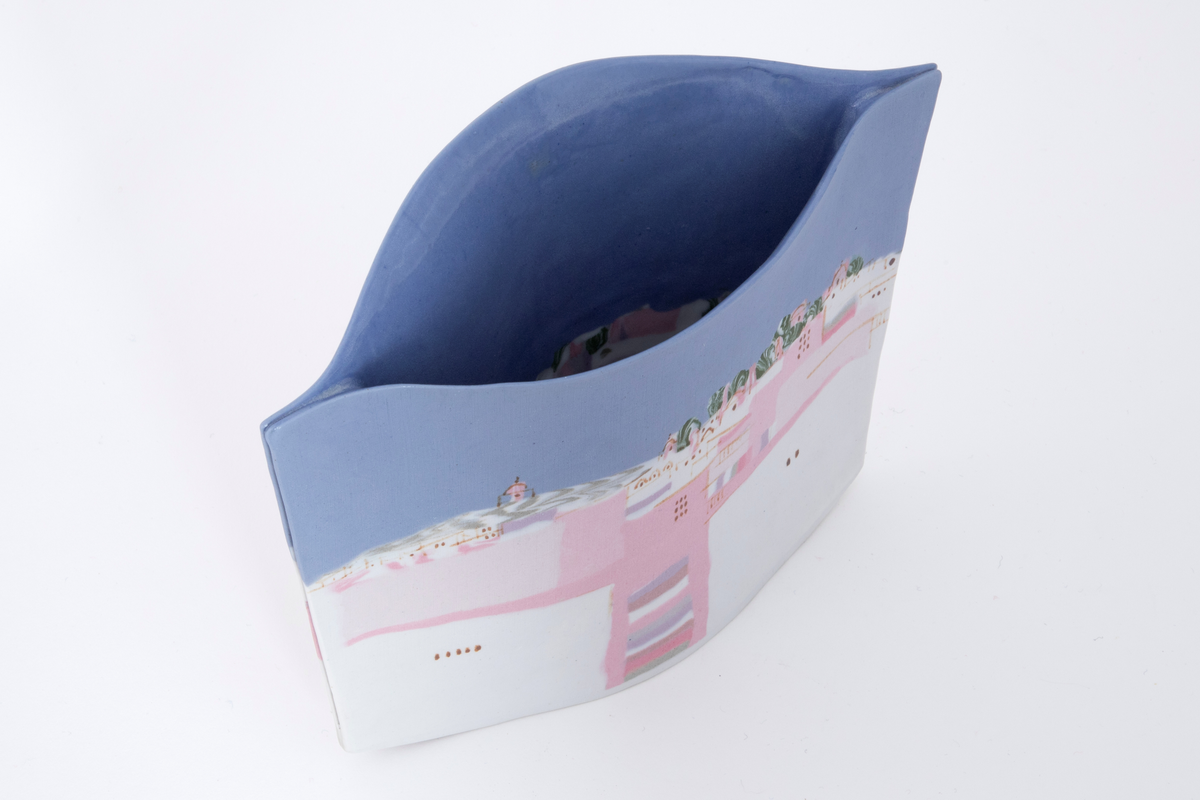 Flat vase sammensatt av to porselensflater. Den ene flaten er konveks oventil mens den andre er konkav. Begge flater prydes på inn- og utside av motiv i blått, hvit, rosa og grønt forestillende et bylandskap. Motivet er skapt med hjelp av innfarget porselen.