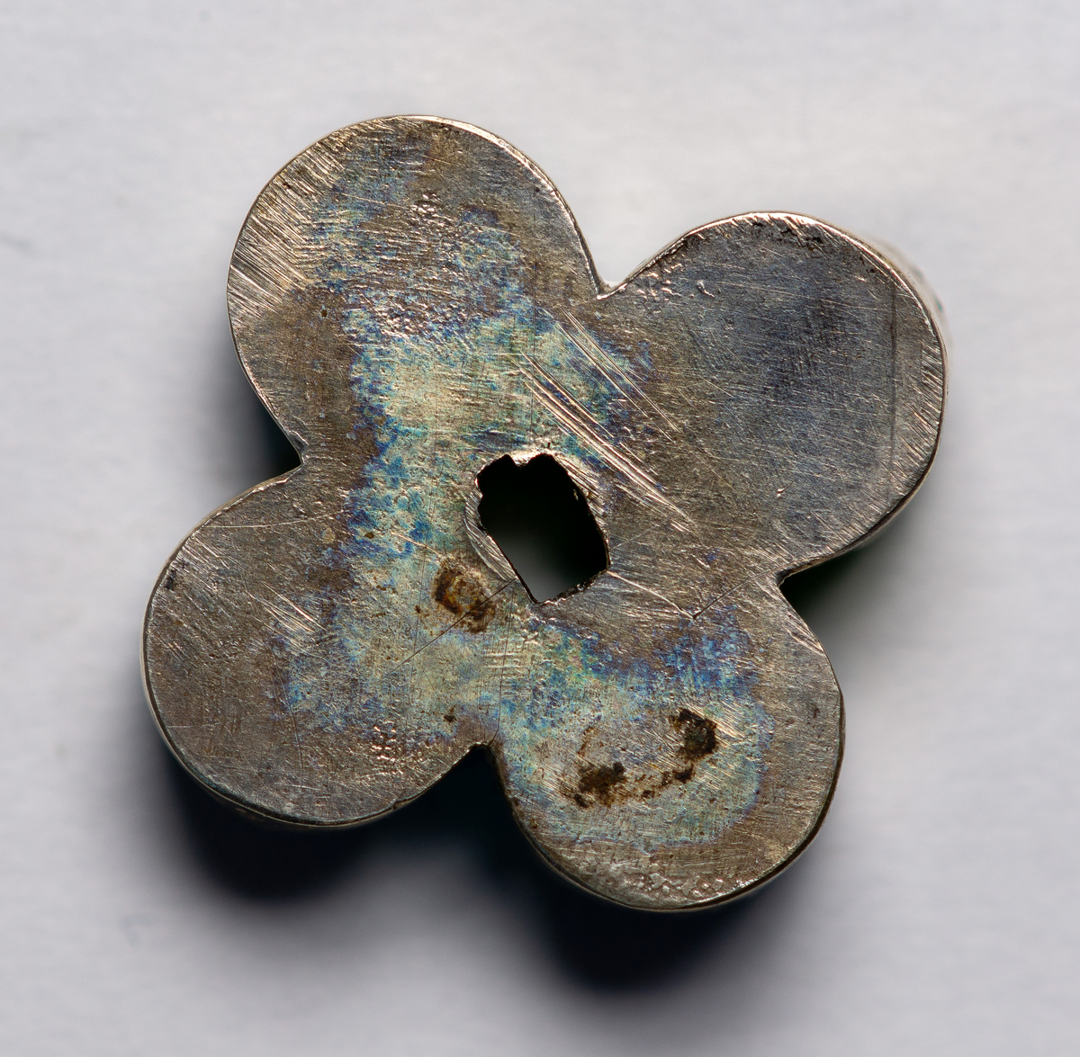 Brudkrona av silverplåt. Oval rak sida av 7 hoplödda plåtar som upptill svänger ut och avslutas i treflikade krön. Buckelornamentik samt svisselerade mönster. Fyrpassformade infattningar av röda och gröna glasstenar på varje flik. Ytterligare dekorerad med påsatta löst hängande förgyllda löv samt halvsfäriska hängen. Kronan avslutas nertill med en påsatt vulst. Stämplar: 13 1/3 (lödighet), LMS (=LM Salvesen), (Ålesunds stadsvapen), 1854.Mått upptill: längd 23 cm, bredd 23 cm.nertill: längd 17 cm, bredd 16 cm, höjd 17 cm.