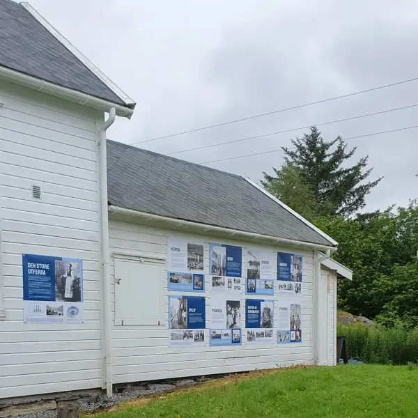 Utstilling med mange plakatar heng på den kvite veggen til fengselet i Prærielandsbyen på Utvandringssenteret