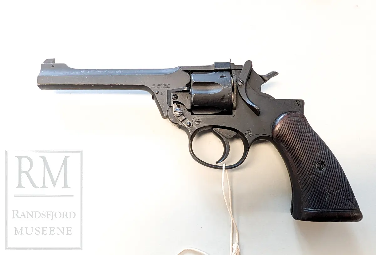 Svart metall. Hylster m belte i kakifarget lerret. Kaliber 38 ACP.