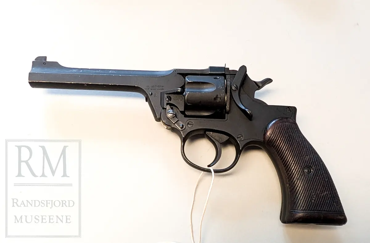 Svart metall. Hylster m belte i kakifarget lerret. Kaliber 38 ACP.