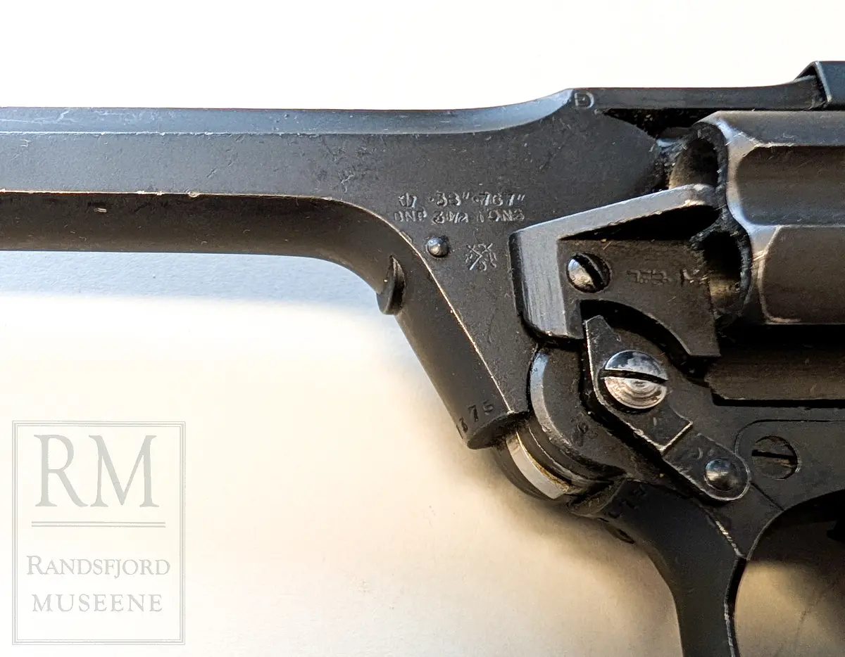 Svart metall. Hylster m belte i kakifarget lerret. Kaliber 38 ACP.