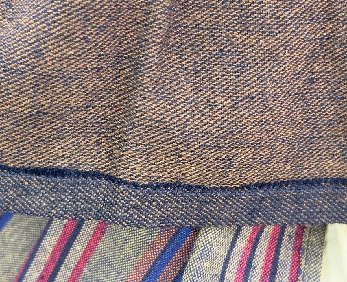 Docka klädd i kvinnlig sockendräkt föreställande Ekshärads socken i Värmland. Huvud och händer sydda av sämskskinn samt kropp av trikåtyg.
