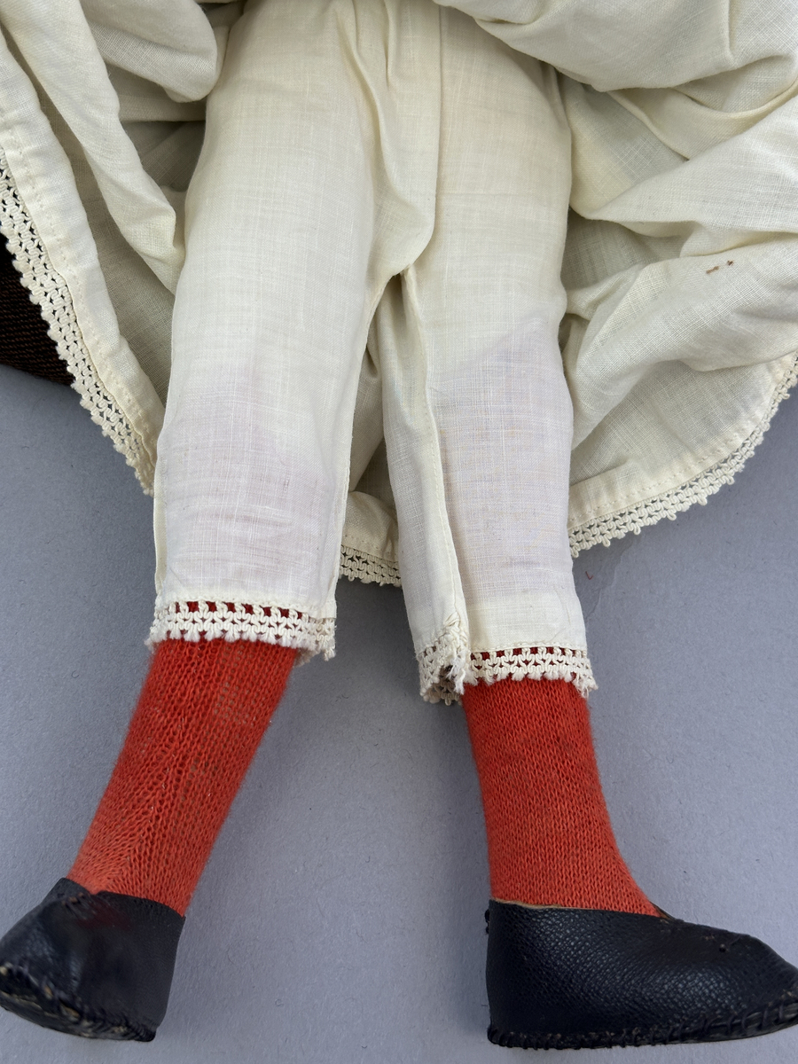 Docka klädd i kvinnlig sockendräkt föreställande Ekshärads socken i Värmland. Huvud och händer sydda av sämskskinn samt kropp av trikåtyg.
