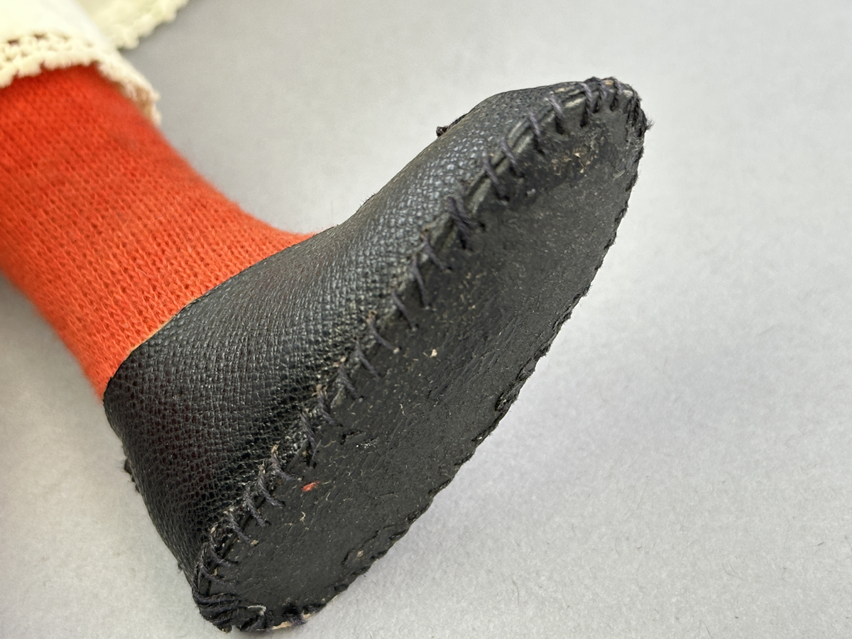 Docka klädd i kvinnlig sockendräkt föreställande Ekshärads socken i Värmland. Huvud och händer sydda av sämskskinn samt kropp av trikåtyg.
