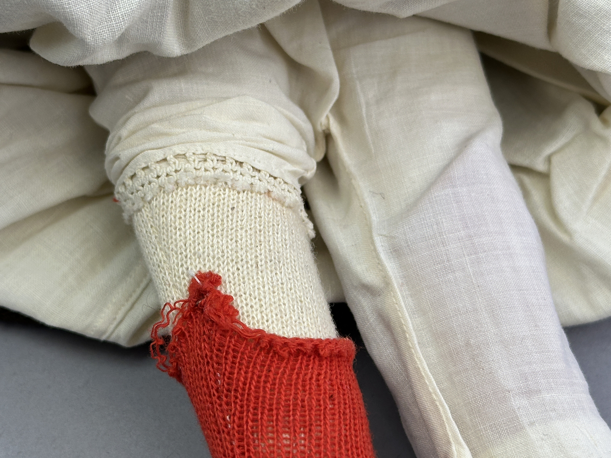 Docka klädd i kvinnlig sockendräkt föreställande Ekshärads socken i Värmland. Huvud och händer sydda av sämskskinn samt kropp av trikåtyg.
