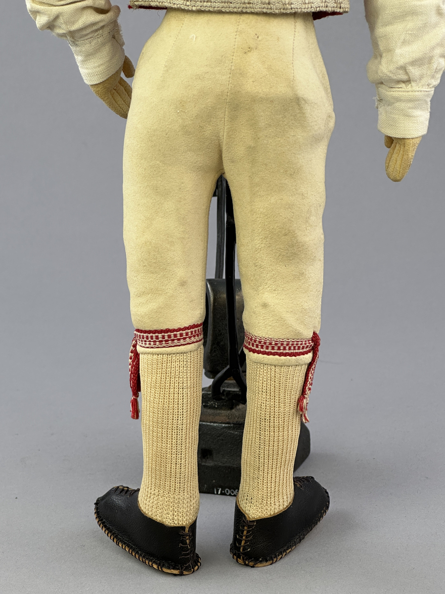 Docka klädd i manlig sockendräkt föreställande Östervallskogs socken i Värmland. Huvud och händer sydda av sämskskinn samt kropp av linnetyg.