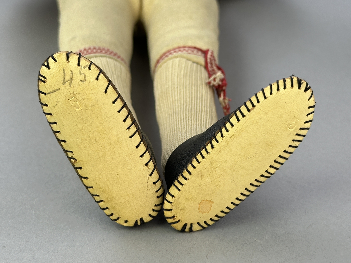 Docka klädd i manlig sockendräkt föreställande Östervallskogs socken i Värmland. Huvud och händer sydda av sämskskinn samt kropp av linnetyg.