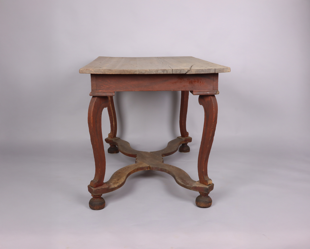 Bord av trä. Trären bordsskiva. 4 svängda ben. Varje ben avslutas med ett halvt svarvat klot. Svängd krysslå sammanför benen i nederkant. Rester av rödbrun färg på underredet.