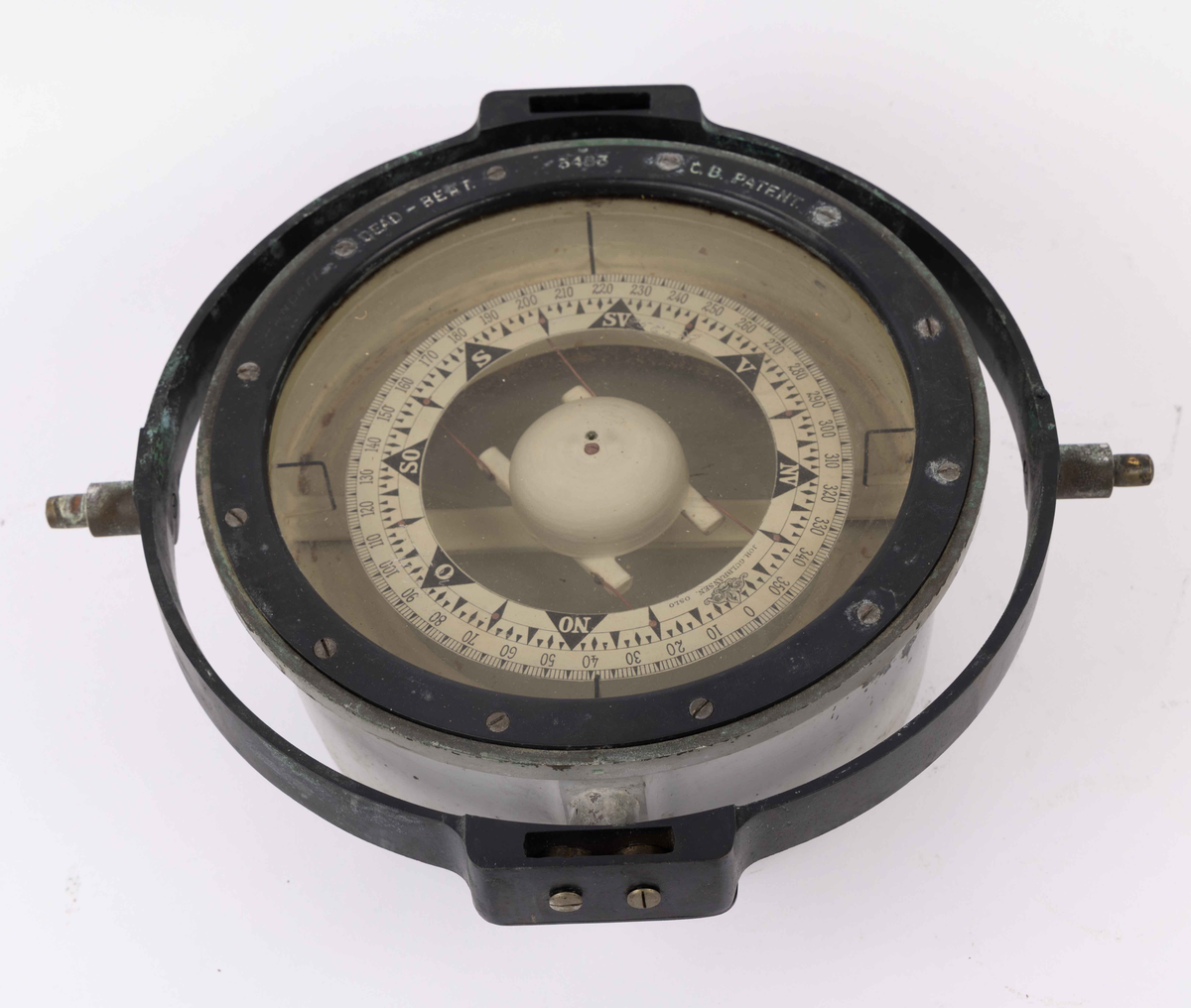 Spritkompass i gråmalt transportkasse av tre. Beregnet til bruk ombord på MS COMETA til BDS. Firkantet transportkasse med løst lokk festet til kasse med hengsel og skinnreim. Lokk med til sammen 20 runde pinner for å holde kompass på plass under transport.