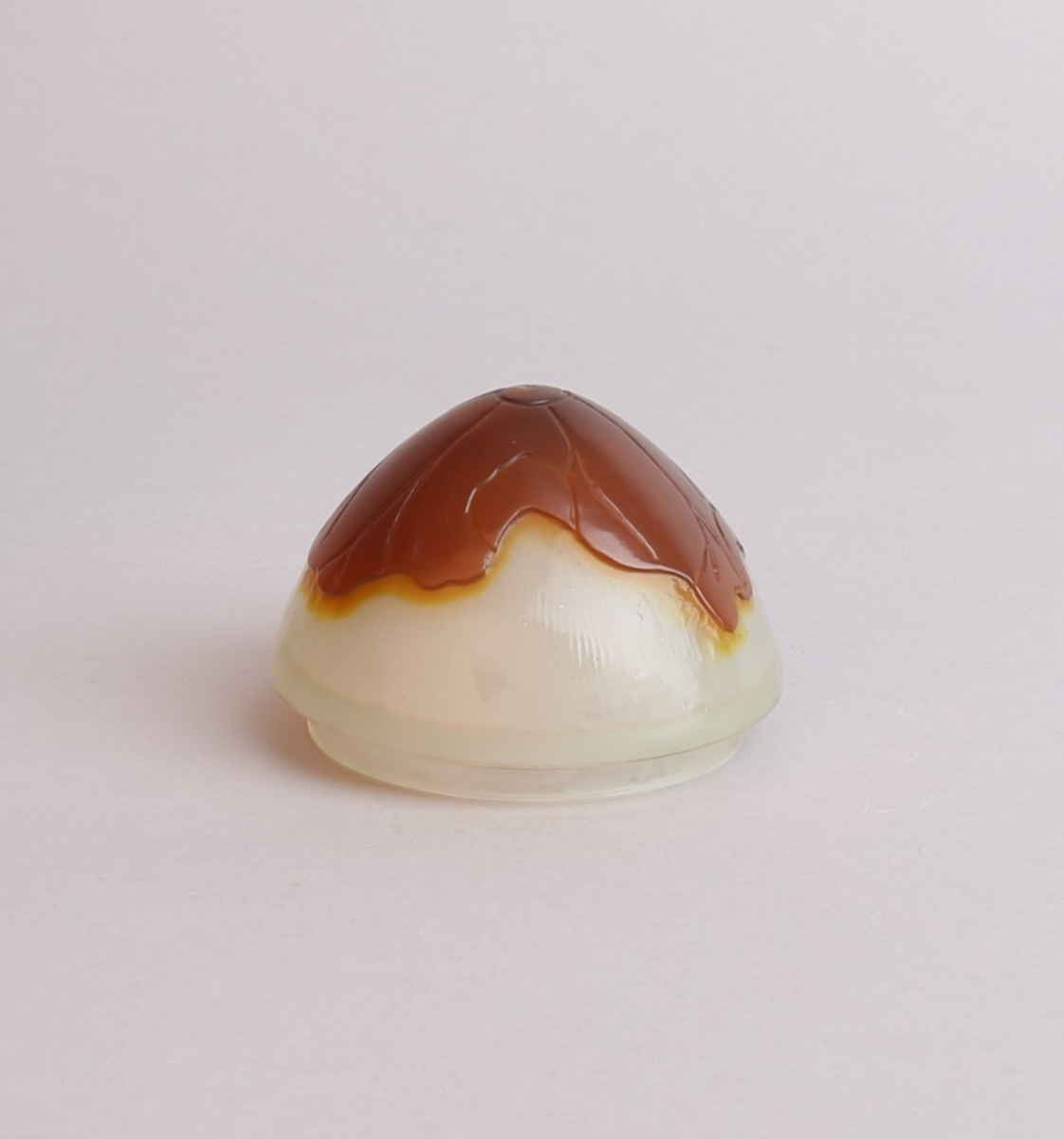 Vase med lokk i melkehvitt opakt overfangsglass. Eggeformet korpus som er dekorert med en gul blomst samt brunlig bladverk i overfangsteknikk. Deler av overflaten er trolig etset.