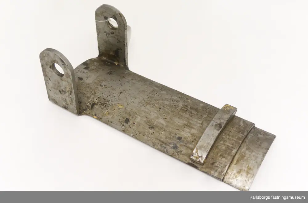 Låda med tillbehör till en 22cm haubits fm/1878, även kallad Crusebjörn. Två laddbryggor, en skruvnyckel till stötbottenmutter, två skruvar till stötbottenstjälk och en bricka till stötbotten. Tillbehören inkom till Armémuseets samling 1933 från Karlsborgs tygstation innan de hamnade hos Karlsborgs fästningsmuseum.