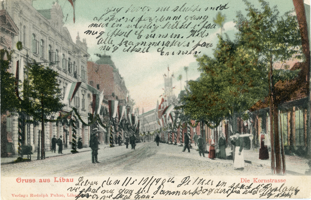 Brevkort adresserat till sjuksköterskan Amanda Palm, 1904. Gatumotiv från Libau, Die Kornstrasse. Verlag: Rudolph Puhze, Libau.
Text överst på kortet: "Jag .. .. nu sluta med af skriva for denne gang med en venlig hilst i fra mig Aksel Enundsen. Hils alle kamerater? i fra mig Aksel Enundsen.
Text nedre del av kort: " Libau den 11/12 1904. .. .. en stund i Ryssland. Vi skal nu gå til Danmark og der ifra ved jag ikke ... ... ...?"