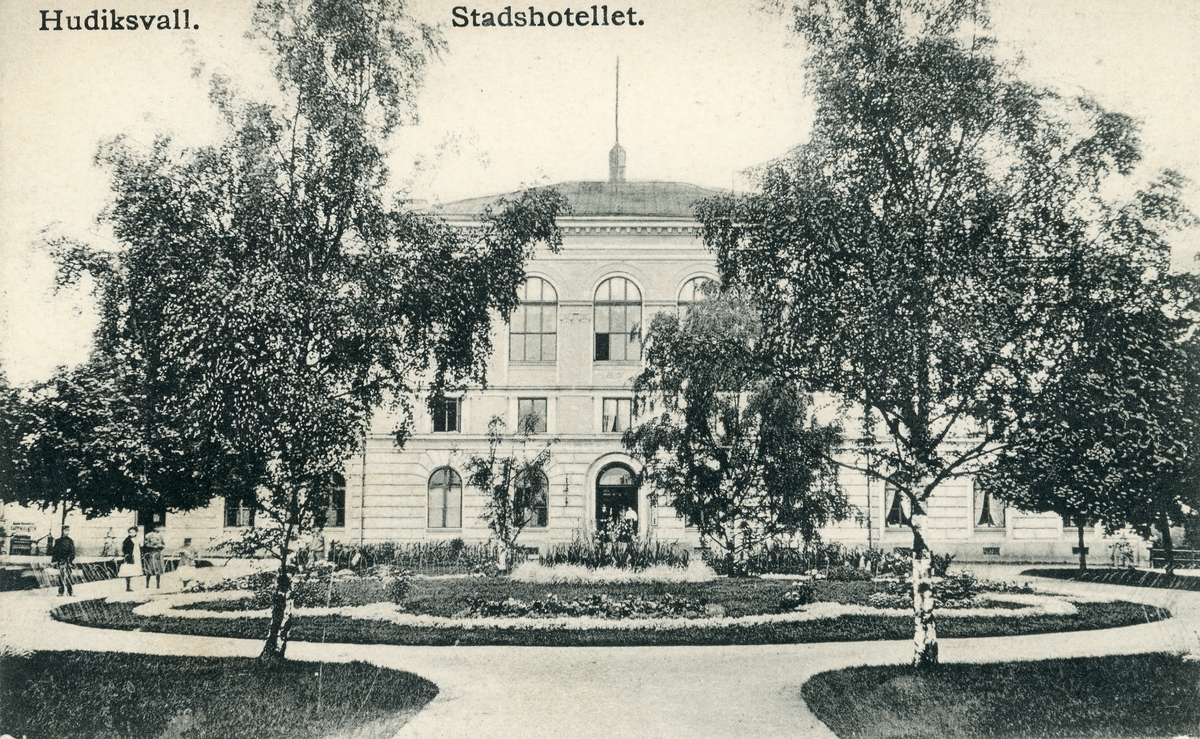 Brevkort adresserat till sjuksköterskan Amanda Palm.
Motiv av Stadshotellet i Hudiksvall med blomplanteringar på hotellets gårdsplan samt björkträd.
Text på baksidan: "H-svall d. 18/8-08. De hjertligaste gratulationer på namnsdagen från oss alla! Välkommen åter! Underätta när du kommer! Ber nu min obekanta helsning till Din Mor. Vännen Lina".