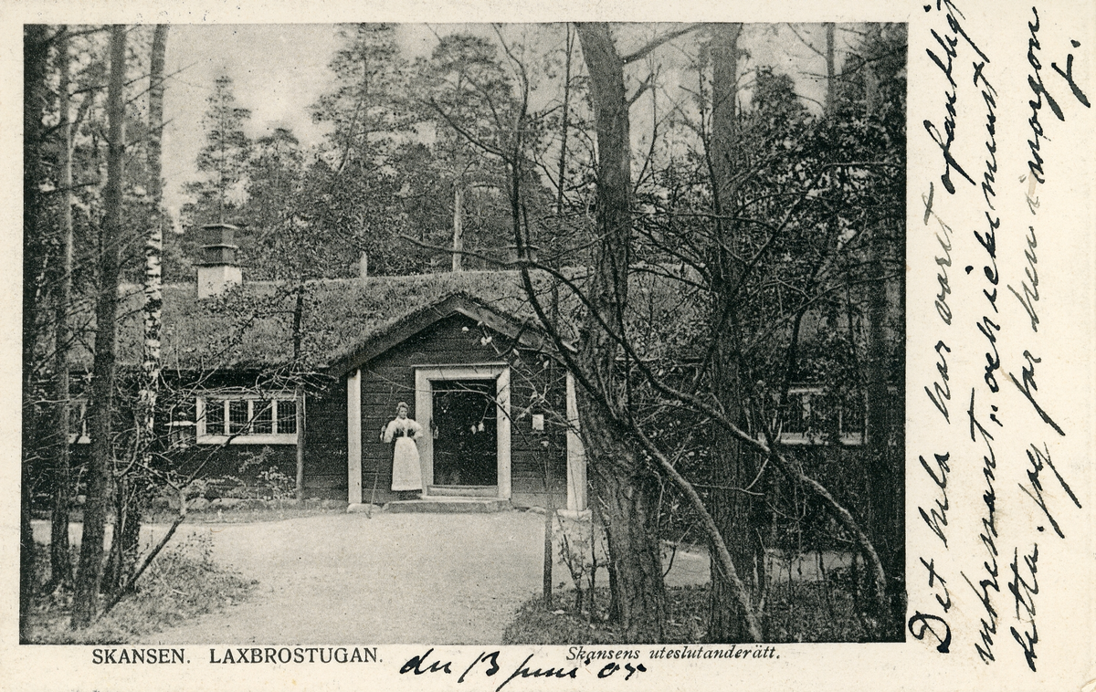 Brevkort adresserat till sjuksköterskan Amanda Palm.
Motiv av Laxbrostugan på Skansen med en kvinna i hembygdsdräkt utanför.
Text på framsidan: "den13 juni 05. Det hela har varit ofantligt intressant och icke minst detta. Jag far hem imorgon. J".
