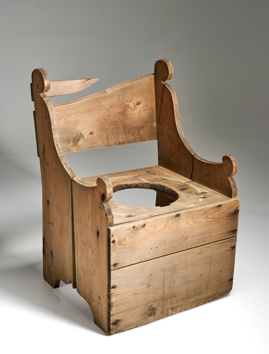 En dostol av ubehandlet tre. Formen er firkantet og den er noe grovt snekret. Setet består av to brede treplanker som er satt sammen ved hjelp av not og fjær. I midten er det skåret ut et sirkulært hull med diameter 29cm. Ryggen består av en bred treplate som er noe ødelagt. Platen dekker ikke hele ryggen. Sidene består av to treplater med enkel utskjæring oppe og nede. I front nede er det festet to brede treplater. Bak nede er det festet en smal treplanke.