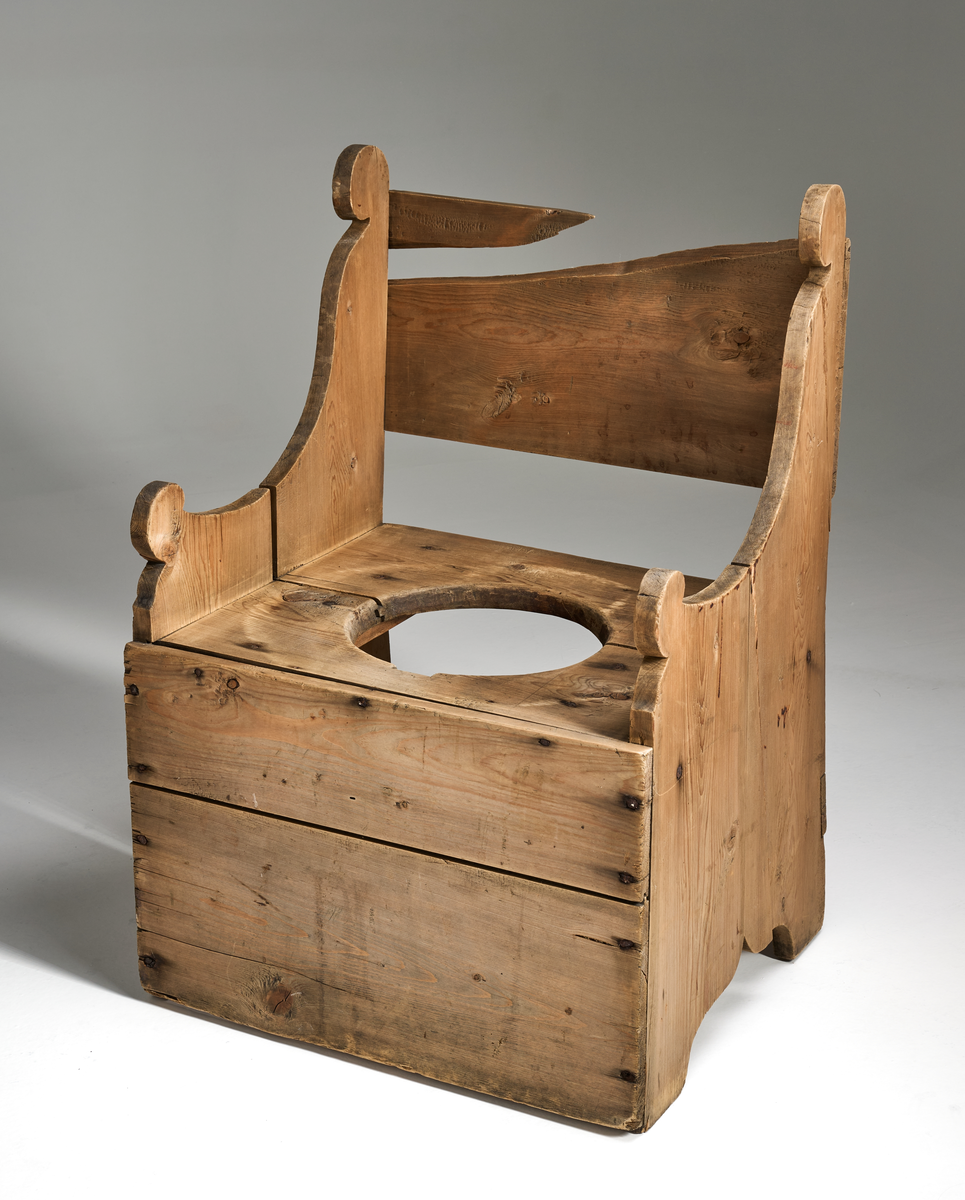 En dostol av ubehandlet tre. Formen er firkantet og den er noe grovt snekret. Setet består av to brede treplanker som er satt sammen ved hjelp av not og fjær. I midten er det skåret ut et sirkulært hull med diameter 29cm. Ryggen består av en bred treplate som er noe ødelagt. Platen dekker ikke hele ryggen. Sidene består av to treplater med enkel utskjæring oppe og nede. I front nede er det festet to brede treplater. Bak nede er det festet en smal treplanke.