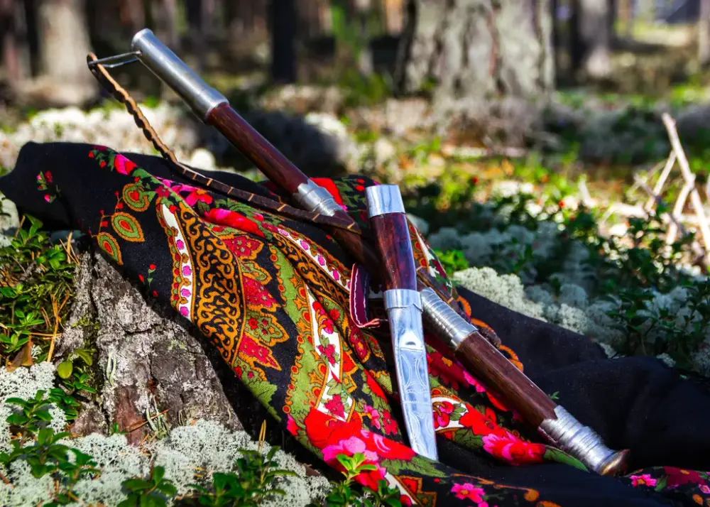 Et fargerikt tørkle som ligger på en skogbunn men en prydkniv oppå.