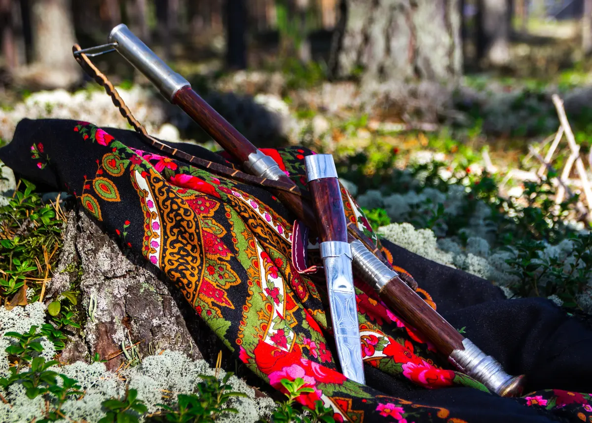 Et fargerikt tørkle som ligger på en skogbunn men en prydkniv oppå.