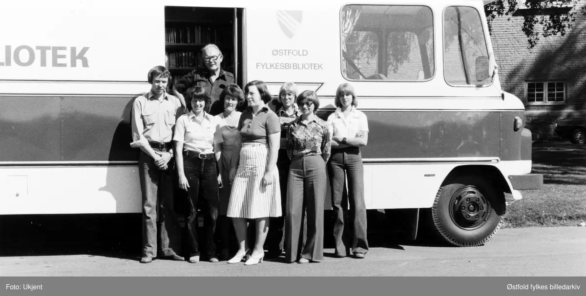 Østfold fylkesbibliotek, ansatte utenfor bokbussen, Østfold rullende bibliotek. Bokbussjåfør Viggo Nilsen i døra. Bakerst til venstre: Svein E. Nilsen. Til høyre for han Anita Alfredsen. Nr. 2 fra høyre er distriktsbibliotekar Irene Bergmann.