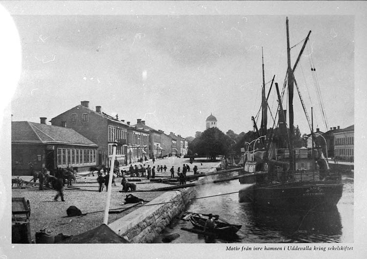 Medföljande text: "Motiv från inre hamnen kring sekelskiftet. Ångfartyget "Magne" av Göteborg lossar timmer till tändsticksfabriken".