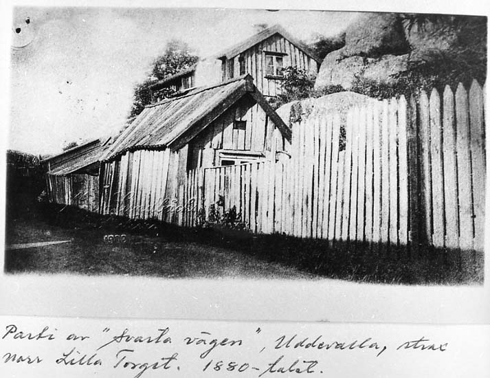 Medföljande text: "Parti av "Svarta vägen". Uddevalla strax norr Lilla Torget. 1880-talet".