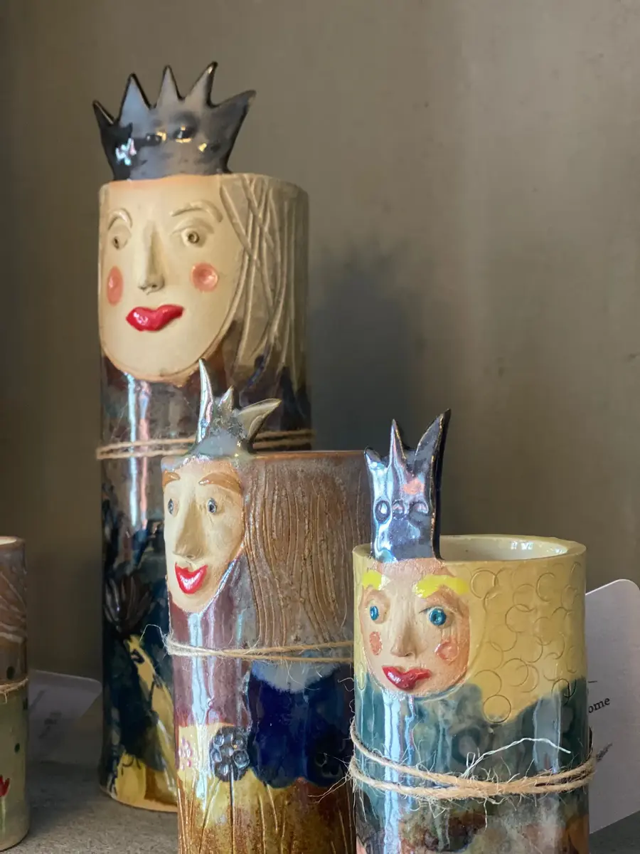 Tre keramikvasar i olika storlekar. De har ansikten och kronor so sticker upp från kanten och mycket färger.
