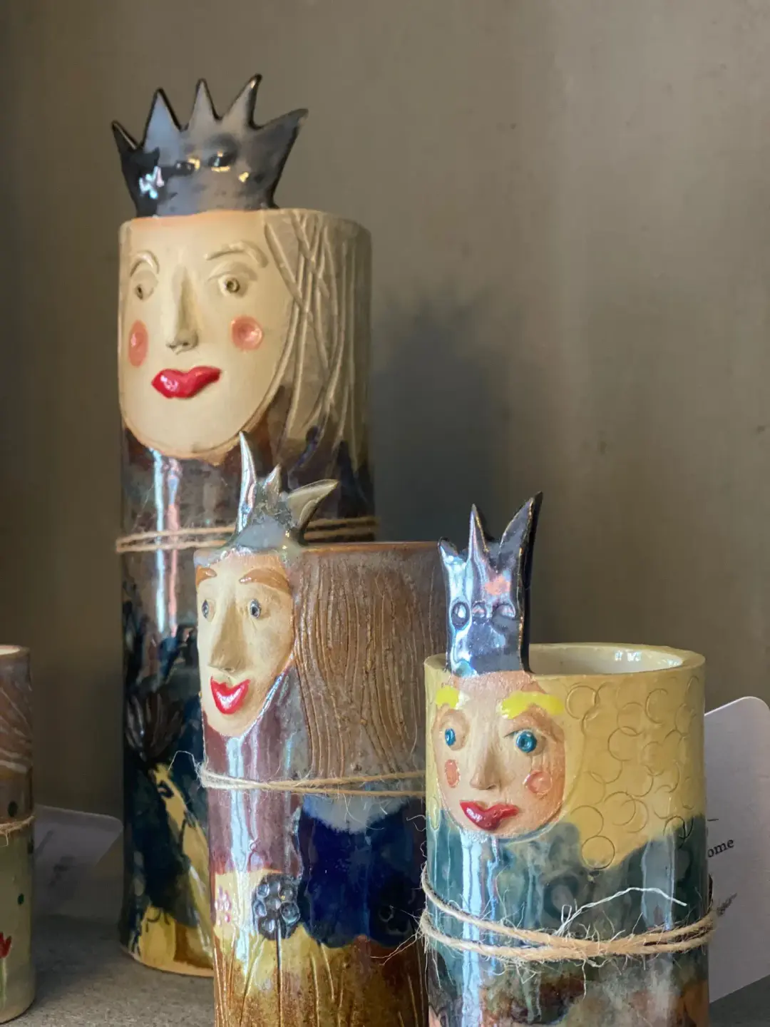 Tre keramikvasar i olika storlekar. De har ansikten och kronor so sticker upp från kanten och mycket färger.