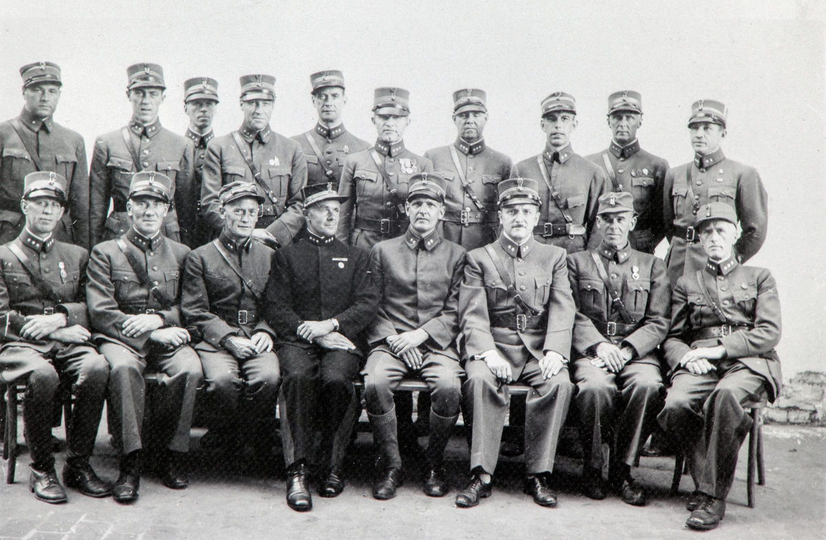 Gruppe 18: norske offiserer i militæruniform, Schildberg fangeleir i Polen under 2. verdenskrig, krigsfanger, nr. 2 fra venstre: Kaptein Knut Stai (1898-1986), nr 4 fv: kaptein Teodor Koller fra Ringsaker. (Fjeld) Bakre rekke nr. 6 f.v. Kaptein Sigvard Tallaksen, han ble arrestert 16.08.1943, og deretter sendt til Shildberg fangeleir i Polen. Senere overført til Luckenwalde hvor han satt frem til freden.