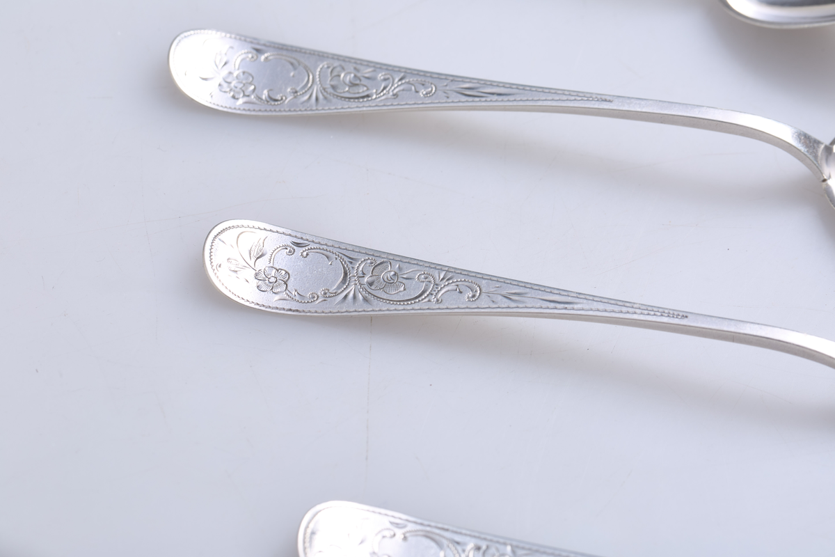 Seks teskjeer i sølv med dekorert håndtak.