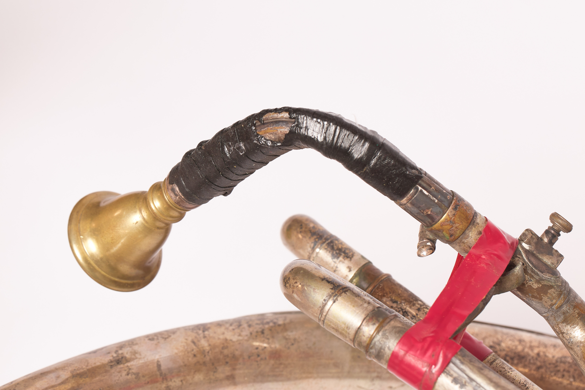 Ess-tuba produsert av Brødrene Schuster i Markneukirchen, Tyskland. Blåse - ventilinstrument. Sjalstykke med to ringer, når og tre ventiler. Bæres. Bygget i ring, rundt hals på skuldrer.