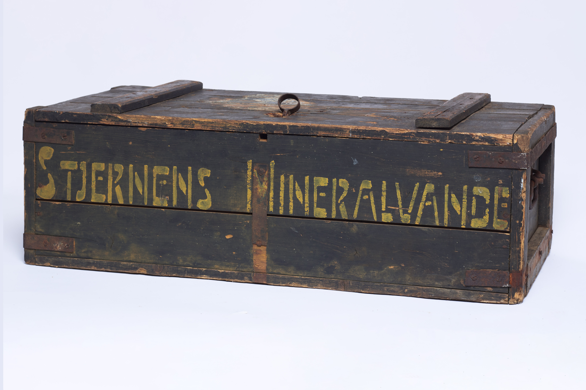 Seltersflaske med patentkork. Korken er merket med "Hortens Bryggeri". Flasken er oppbevart sammen med flere andre flasker i en trekiste med lokk. På trekisten står det "Stjernens Mineralvande" på siden.