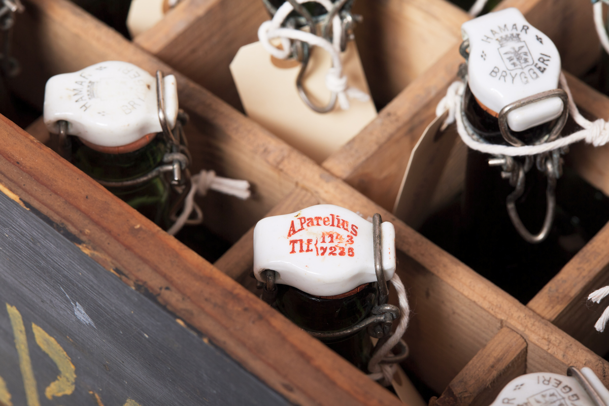 Seltersflaske med patentkork. Korken er merket med "Hortens Bryggeri". Flasken er oppbevart sammen med flere andre flasker i en trekiste med lokk. På trekisten står det "Stjernens Mineralvande" på siden.