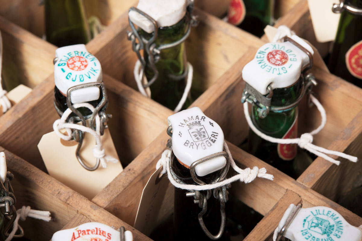 Seltersflaske med patentkork. Korken er merket med "Hortens Bryggeri". Flasken er oppbevart sammen med flere andre flasker i en trekiste med lokk. På trekisten står det "Stjernens Mineralvande" på siden.