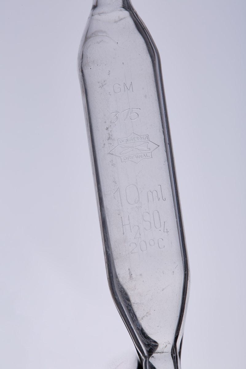 Volumetrisk pipette på 10ml, laget av glass med tre utblåsninger. Den har et smalt glassrør med to runde utblåsninger, og har en tydelig utblåsning midt på, som markerer det nøyaktige volumet den er kalibrert for. Den har en bredere åpning øverst for å suge opp væske, og en tynn, presis spiss nederst for å dryppe ut væsken. Pipetten brukes i laboratorier til å måle opp og overføre en nøyaktig mengde væske. 

Denne er enten brukt på Kapp Melkefabrikker eller ved Nestlés fabrikk på Hamar.