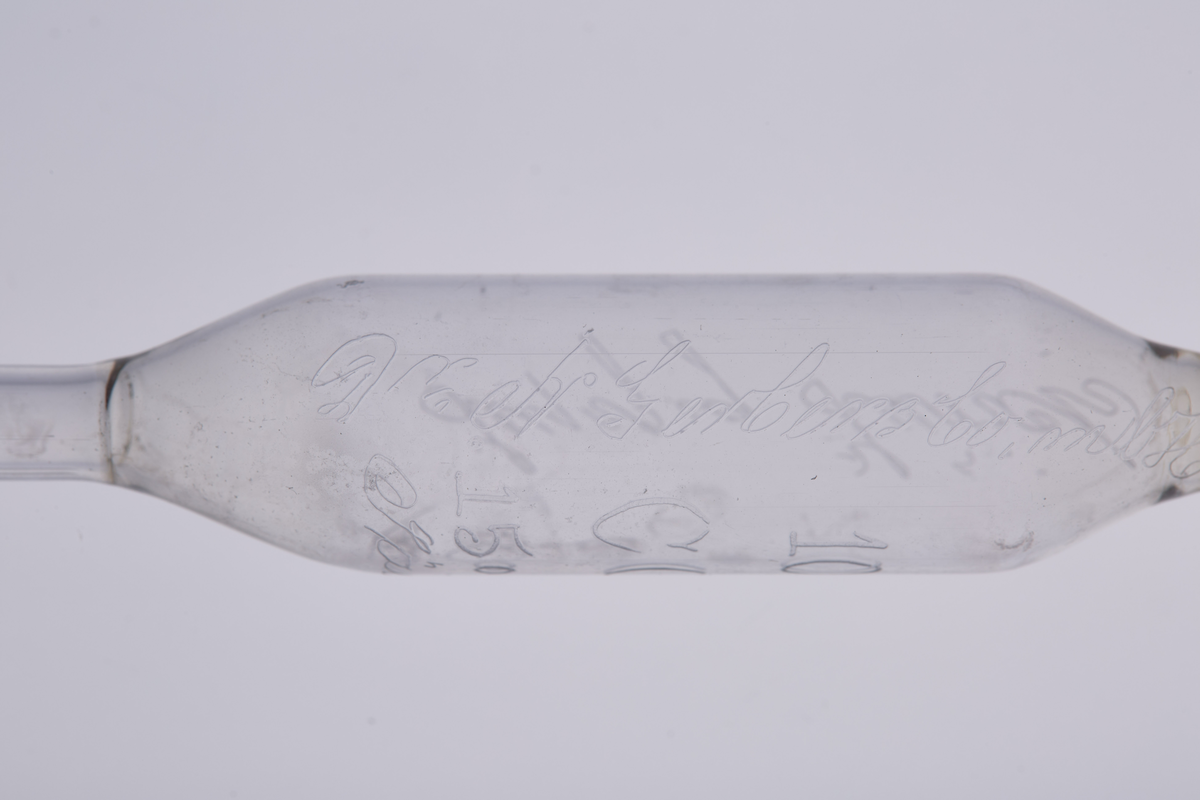 Volumetrisk pipette på 10ml, laget av glass med tre utblåsninger. Den har et smalt glassrør med to runde utblåsninger, og har en tydelig utblåsning midt på, som markerer det nøyaktige volumet den er kalibrert for. Den har en bredere åpning øverst for å suge opp væske, og en tynn, presis spiss nederst for å dryppe ut væsken. Pipetten brukes i laboratorier til å måle opp og overføre en nøyaktig mengde væske. 

Denne er enten brukt på Kapp Melkefabrikker eller ved Nestlés fabrikk på Hamar.