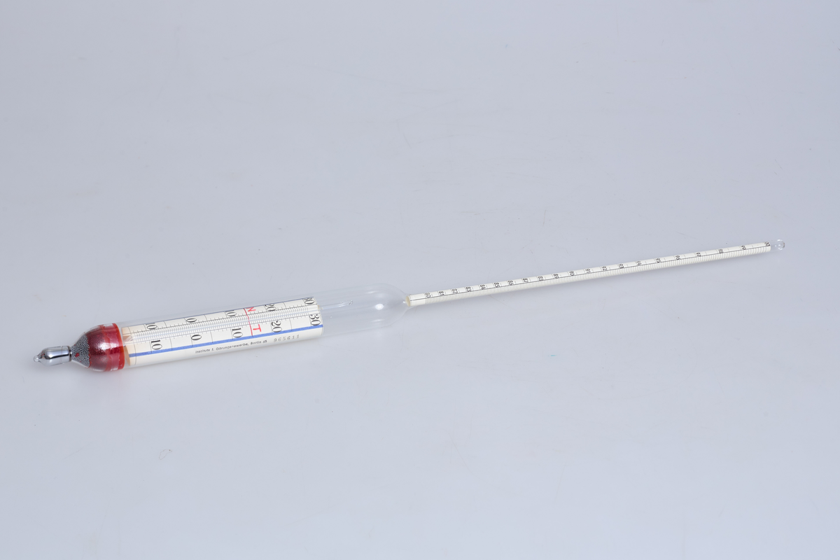 Alkometer eller spritmåler i glass, brukt til å måle alkoholstyrken i brennevin ved Toten Brenneri A/L.

Instrumentet består av en kort, tykk glasskropp med en rødfarget vekt i bunnen, og et langt, tynt målerør som stikker opp. På det tynne røret er det en måleskala som viser 80 til 100 vol% alkohol, basert på Gay-Lussac-skalaen (volumprosent). 

På den nederste delen av instrumentet er det en tilleggsskala med tall fra 10 til 0 til 30, samt merkene "N" og "T". Denne brukes sammen med et innebygd Celsius-termometer for å korrigere avlesningen etter væskens temperatur. Instrumentet er kalibrert for bruk ved 15°C 

Ligger i original papp hylse merket: 80-100 vol %, TOTEN BRENNERI A/L og NR 965611



Alkoholmeter med termometer
spritmåler med gradestokk
måle alkoholmengde i væske